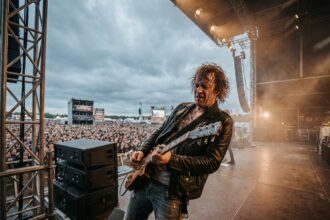 Guitariste passionné sur scène lors d'un grand concert de rock en plein air devant une foule immense