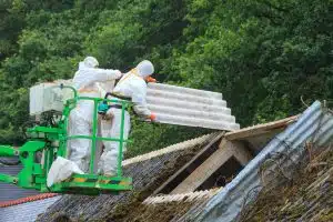 Ouvriers d'une entreprise de démolition en train de retirer des panneaux d'amiante d'une vieille toiture