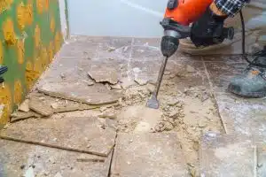 marteau burineur en train de détruire un carrelage lors de travaux de démolition dans une maison