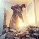 Ouvrier d'une entreprise de démolition en train de détruire une cloison intérieure